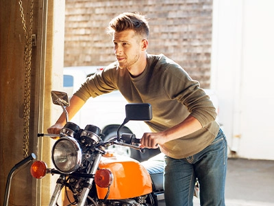 Man pushing his motorcycle into a building