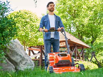 Person pushing an orange lawn mower