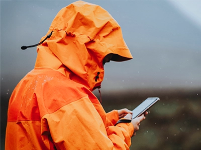 Person wearing a raincoat while looking at their phone
