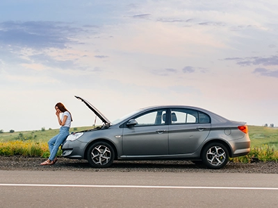 Person leaning against a car on the side of the road