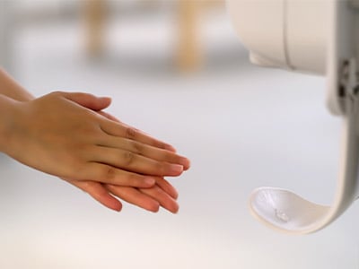 Rubbing hands together after getting sanitizer from touchless dispenser