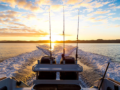 Boat on the water going away from the setting sun